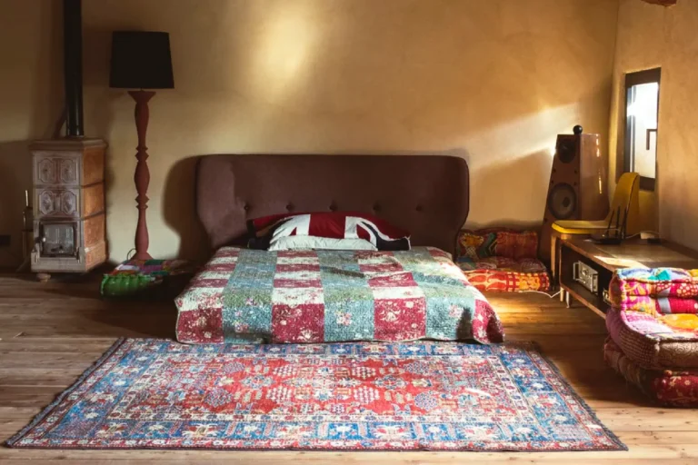 Camera in mansarda della Tana del Tasso con letto basso, stufa in maiolica e cuscini da terra