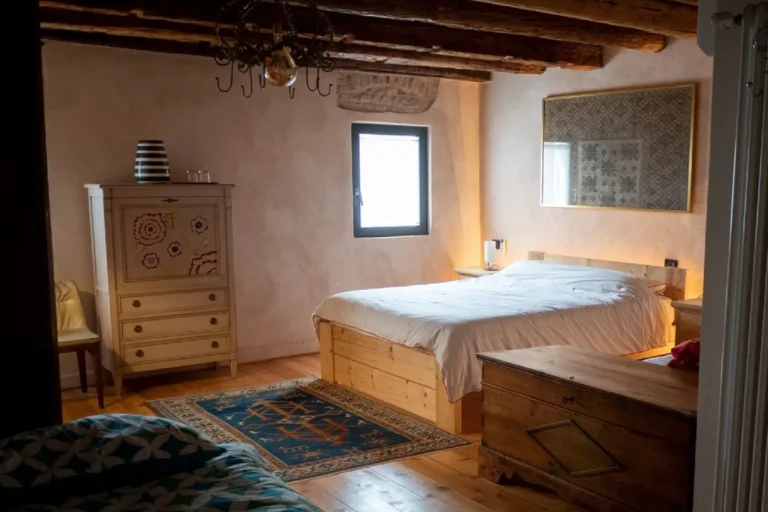 Camera matrimoniale con travi a vista e pavimento in legno nel casale della Tana del Tasso