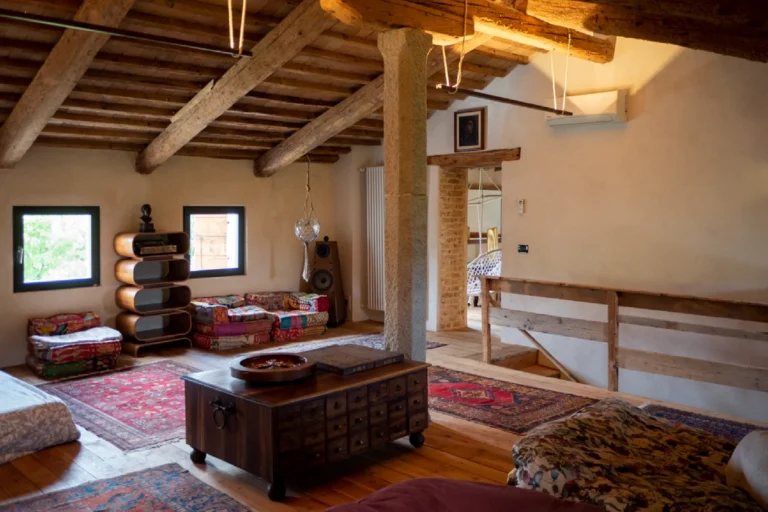 Sala della pratica in mansarda con travi a vista e cuscini da terra alla Tana del Tasso