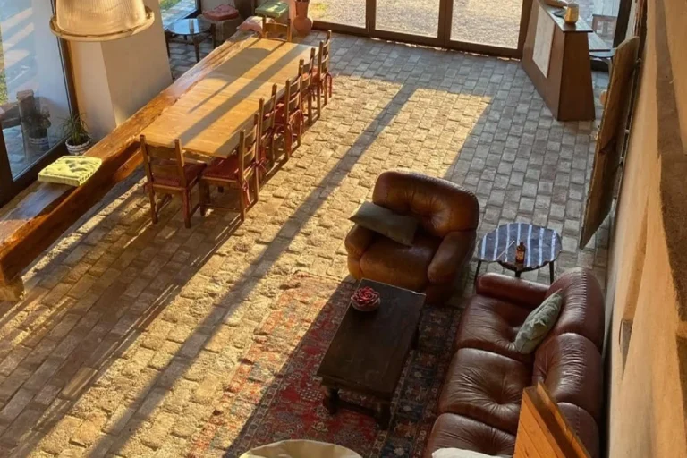 Salone della Tana del Tasso visto dall'alto, con tavolo conviviale in legno e divani in pelle